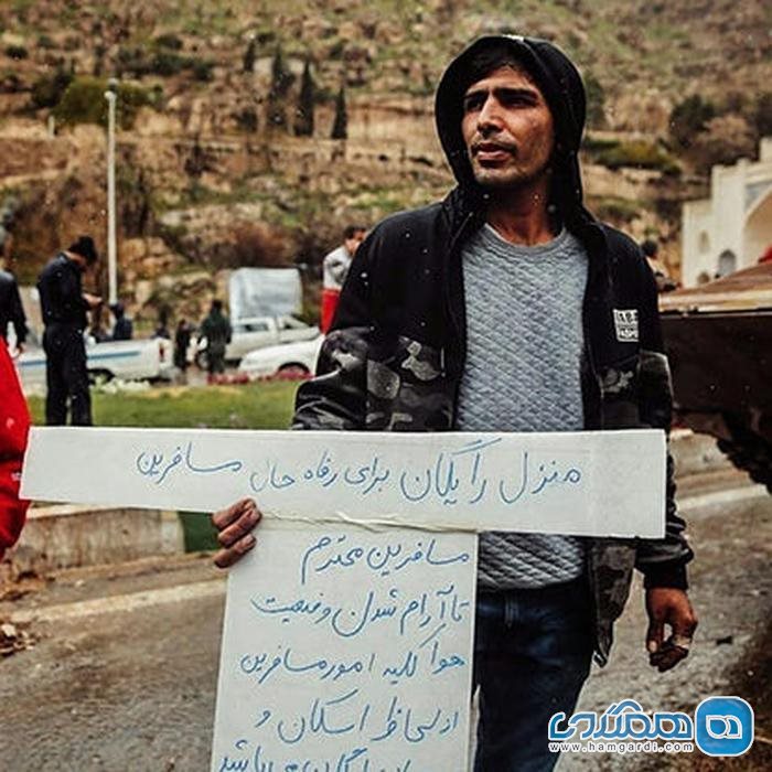 مردی با پلاکارد سخاوت در سیل شیراز