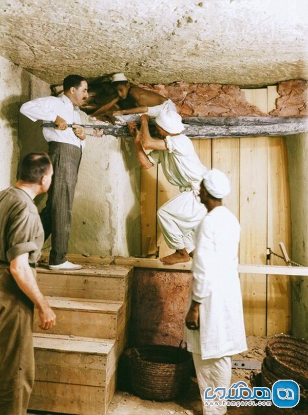 هاوارد کارتر (در بالای پله ها)، آرتور کالندر و کارگران مصری در حال برداشتن دیوار بین اتاق پیشگاه و اتاق تدفین